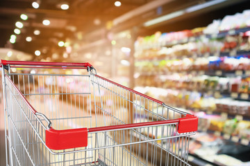 Wall Mural - supermarket grocery store with fruit and vegetable shelves interior defocused background with empty red shopping cart