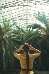 Back view fit exotic woman watching palm trees in a tropical gar