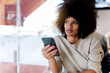 © santypan - Portrait of attractive afro woman using mobile phone at the coffee shop