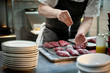 © Liz Clayman - Chef sprinkling salt on meat in a restaurant kitchen