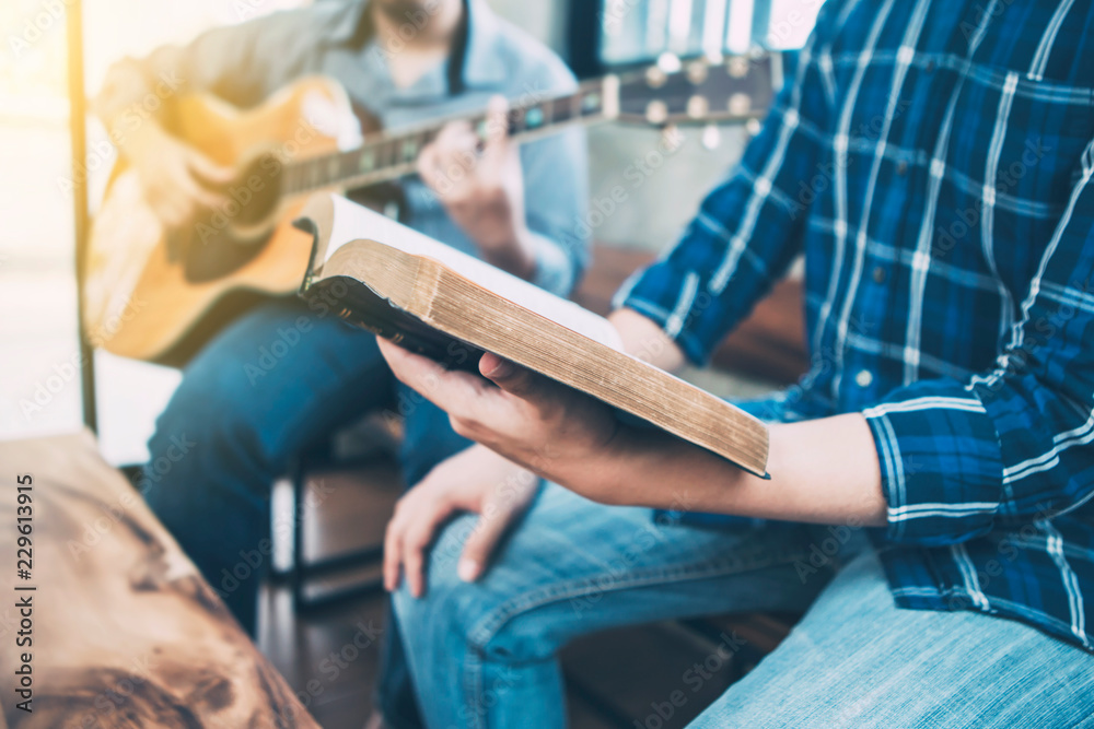 close up of a man holding hymn books and sing a song while his friend playing guitar, praise and worship concept - obrazy, fototapety, plakaty 