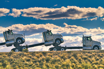 Large Truck towing two other trucks under moody clouds 