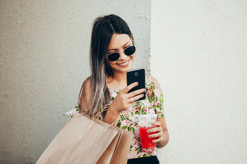 Shopper woman hand shopping with a smart phone and carrying bags