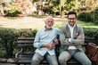 © bnenin - Portrait of elegant senior and young man sitting on a bench in the park.