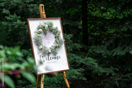 Cuadros en Lienzo Blank signpost pointer on a wooden easel in a frame with a wreath