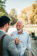 © bnenin - Two men handshaking at the park. Senior and young man meeting at the park. Family reunion concept.