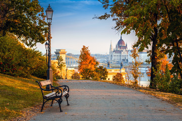 Wall Mural - Budapest, Hungary - Romantic sunrise scene at Buda district with bench, lamp post, autumn foliage, Szechenyi Chain Bridge and Parliament at background
