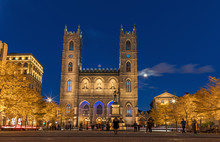 Montreal, Canada, October 20, 2018. Notre Dame Basilica From Montreal And Maisonneuve Monument Illuminated At Night Time, During Autumn Season.  First Neo-gothic Church In Canada.