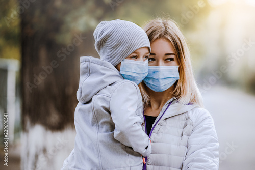 Fotografia, Obraz a girl with a child stands on the road in a protective medical mask