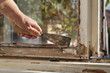 © sima - Worker removing oil window glazing putty using putty knife tool, old window restoration