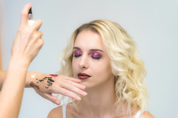 Wall Mural - The work of a professional makeup artist - beautician, makes up a brush on the face on the lips of a beautiful blonde.