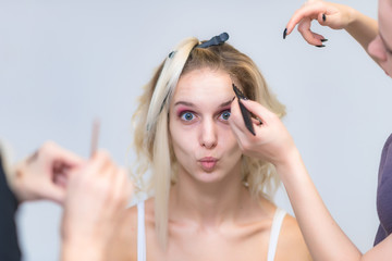 Wall Mural - The work of a professional make-up artist, beautician, makes makeup on the face of a blonde girl with shadows on the eyes.