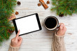 © sosiukin - Christmas online shopping. Female hand touch screen of tablet, top view on wooden bakground, copy space and holding mug of coffee. Winter holidays sales background