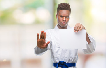 Canvas Print - Young african american man over isolated background wearing kimono holding paper with open hand doing stop sign with serious and confident expression, defense gesture