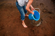 © RooM The Agency - Girl standing on the beach holding a bucket filled with water, United States