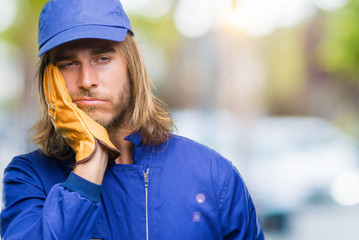 Sticker - Young handsome mechanic man with long hair over isolated background thinking looking tired and bored with depression problems with crossed arms.