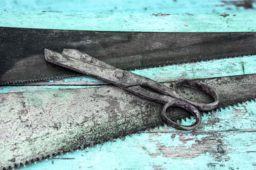 Old metal saws and scissors on a blue wooden table