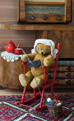 Wall Mural - Teddy bear grandma knitting in a rocking chair in a vintage interior