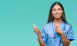 Young arab doctor surgeon woman over isolated background smiling and looking at the camera pointing with two hands and fingers to the side.