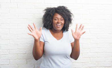 Canvas Print - Young african american plus size woman over white brick wall celebrating crazy and amazed for success with arms raised and open eyes screaming excited. Winner concept