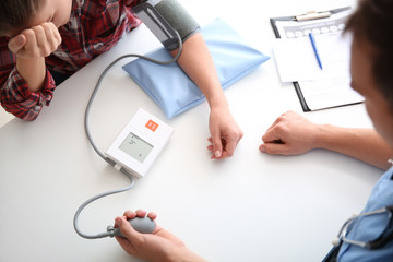 Canvas Print - Male doctor measuring blood pressure of female patient in hospital