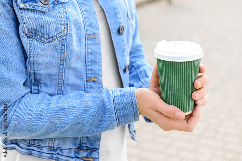 Woman holding paper coffee cup outdoors