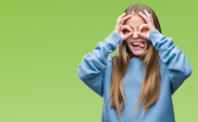 Young beautiful girl wearing winter sweater over isolated background doing ok gesture like binoculars sticking tongue out, eyes looking through fingers. Crazy expression.