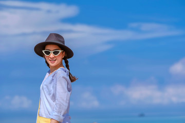 portrait beautiful woman in outdoor the beach with posing relax smile happy in holiday by wear hat and sunglasses fashion sunglasses and bag yellow with blue sky background