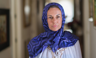 Wall Mural - Middle age brunette arabian woman wearing colorful hijab with a confident expression on smart face thinking serious