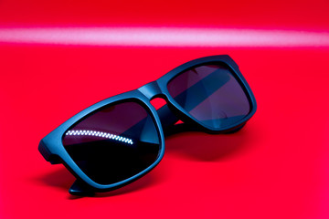 Fashion sunglasses isolated on red background, black plastic.