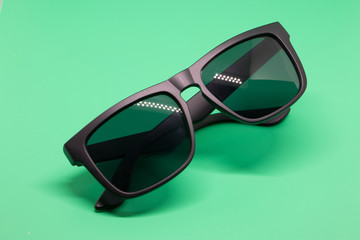 Fashion sunglasses isolated on green background, black plastic.