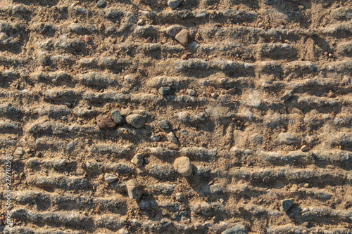 Fotografie, Obraz Rough Grey Sunlit Concrete Background Texture With Lines and Small Stones