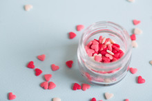 A Lot Of Small Candy In Form Of Hearts In Open Glass Jar On Light Background.