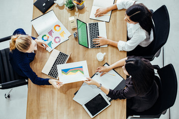 Top view of businessmen and businesswoman standing and stacking hands over table in a meeting with copy space at mobile office. Teamwork, diversity, collaboration concept.