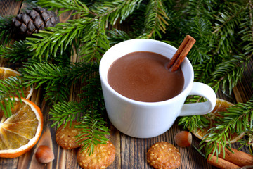 Hot chocolate or cocoa with cinnamon stick in a cup and fir branches. Winter hot drink for cold weather. New year and Christmas concept