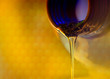 liquid stream of sweet honey flows from the neck of the bottle close-up.