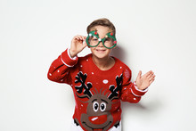 Cute Little Boy In Christmas Sweater With Party Glasses On White Background