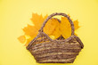 Autumn leaves and a basket on a yellow background, the concept of autumn
