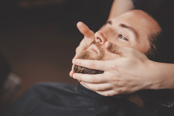 Wall Mural - Barber uses oil massage to grow and strengthen beard to man.