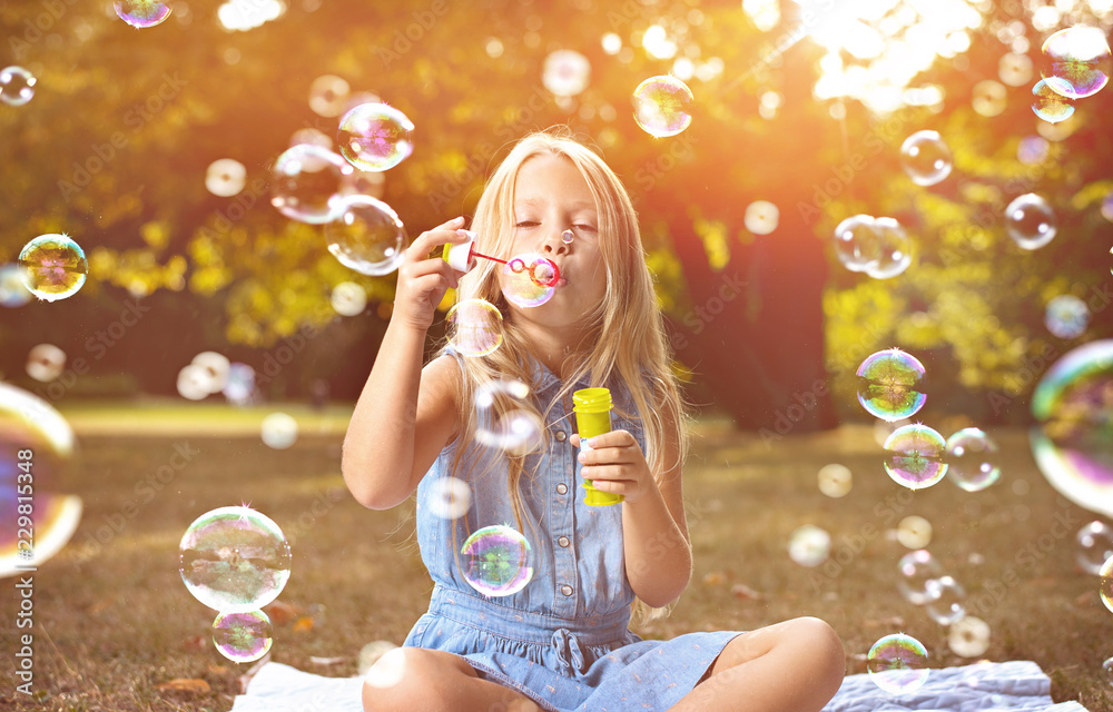 Portrait of a cheerful girl blowing soap bubbles - obrazy, fototapety, plakaty 