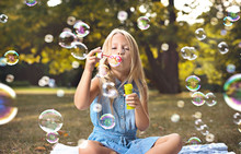 Portrait Of A Cheerful Girl Blowing Soap Bubbles