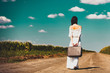© Masson - photo of the beautiful young woman with suitcase  walking on the road