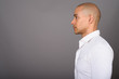 © Ranta Images - Profile view of handsome bald businessman against gray background