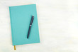A photo of a teal blue journal with a pen, an elegant notebook or planner, shot from above with copy space