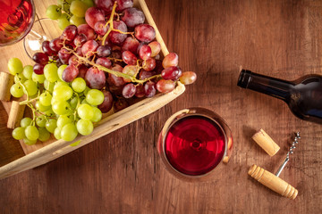 Poster - An overhead photo of wine glasses with a bottle, grapes, a vintage corkscew and a cork, shot from above on a dark rustic wooden background with a place for text