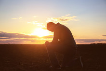 Religious Man Praying Outdoors At Sunset
