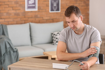 Young man measuring his blood pressure at home