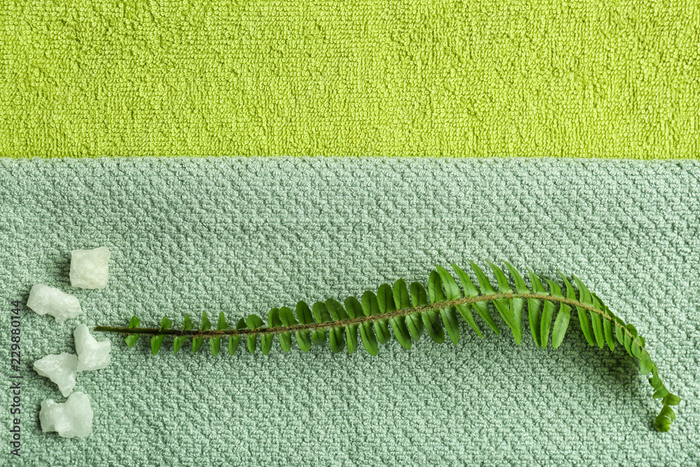 Green leaf on folded clean towels, top view