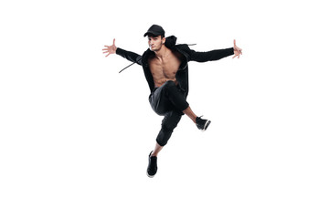 Wall Mural - Young handsome young dancer dressed in black pants, a sweatshirt on a naked torso jumps and spreads his arms to the sides