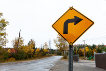 Turn Right Yellow Road Sign That Is Bent, Dented, Cracked And Rusty - 1/2 - Picture Taken In Quebec, Canada, While Autumn Colors Were Very Present. Perspective From The Side Of The Road